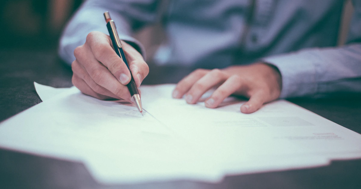 Editor marking up a printed article draft with a red pen